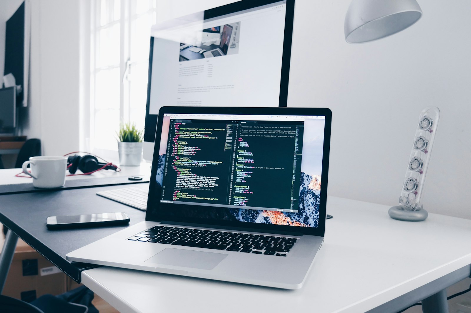 Developer laptop and notebook on bright coworking desk — developer project studio brandable
