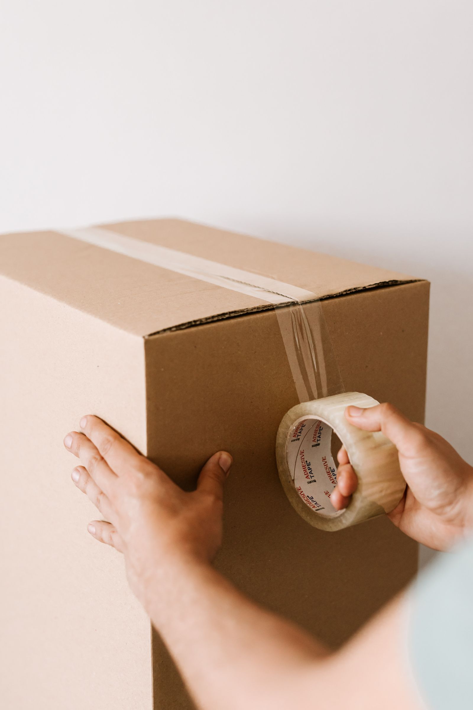 Unbranded kraft cardboard packaging box sealed in bright studio daylight — product editorial, no neon