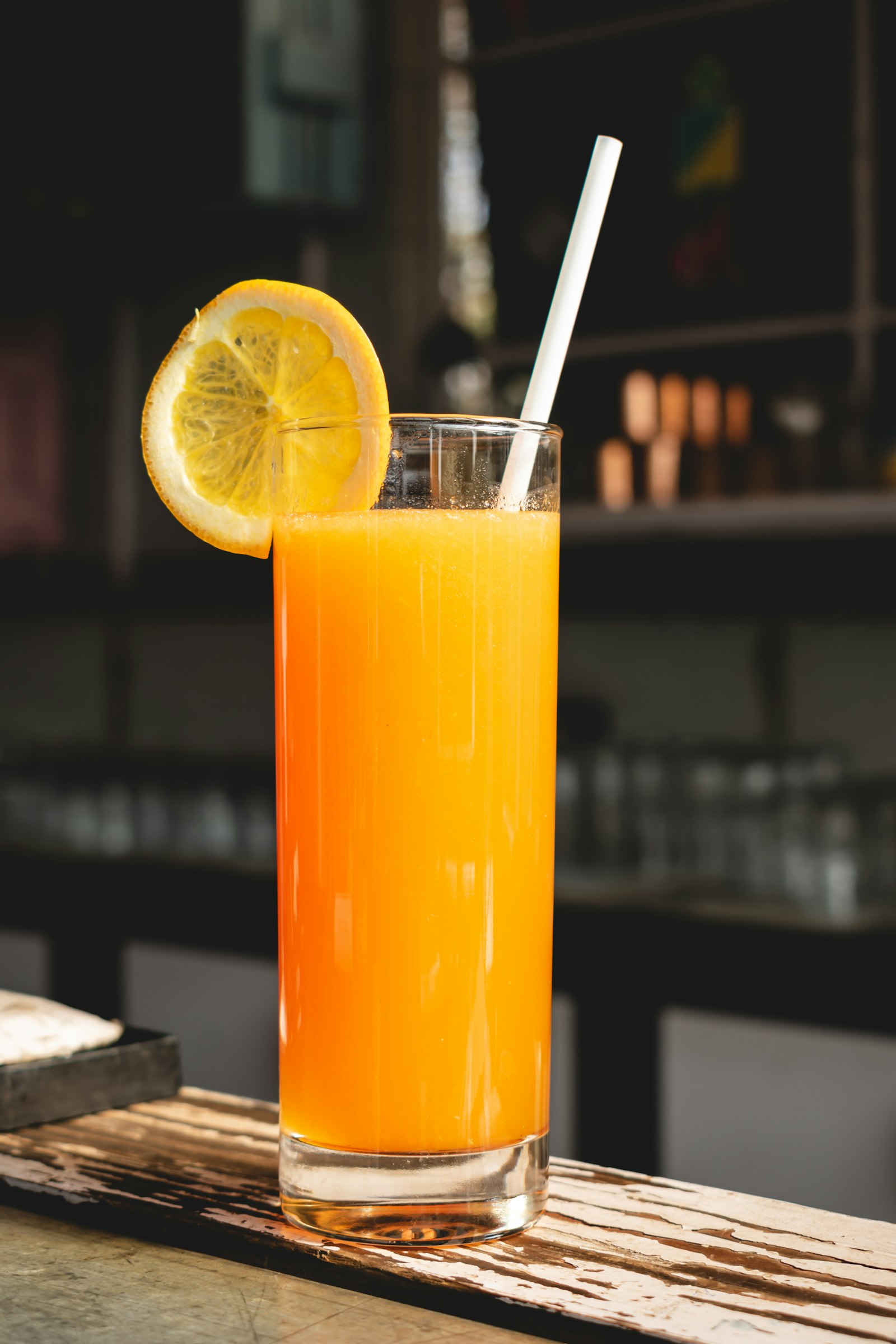 Fresh orange juice in glass with citrus garnish on wood — morning vitality daylight