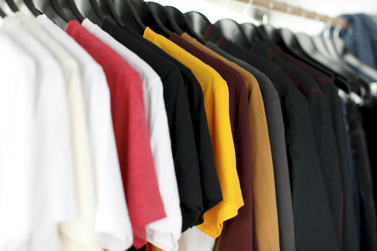 Unbranded streetwear t-shirts and hoodies on clothing rack — apparel editorial daylight
